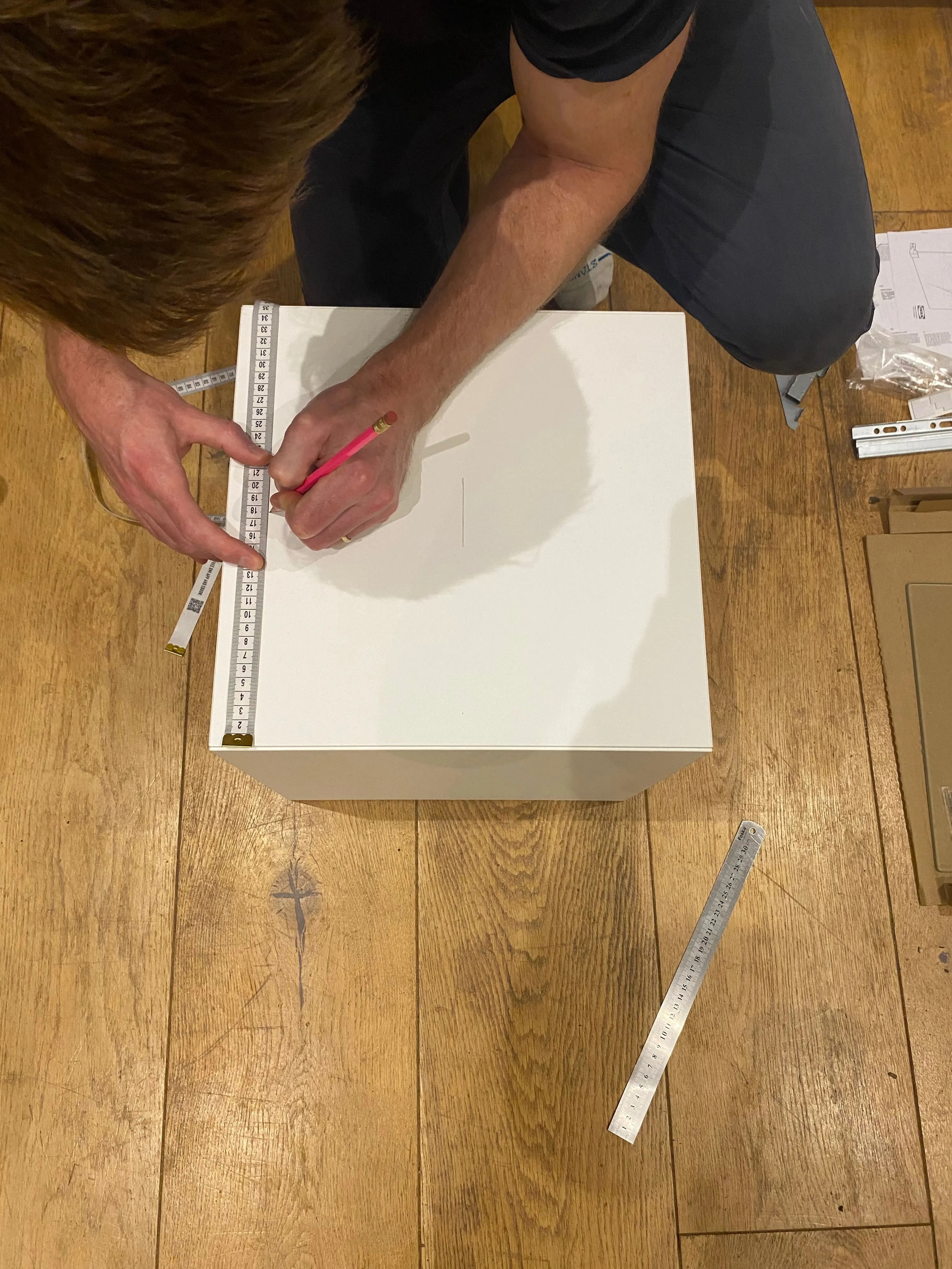 The pencil cross mark on the top panel — the centre point for the hole saw